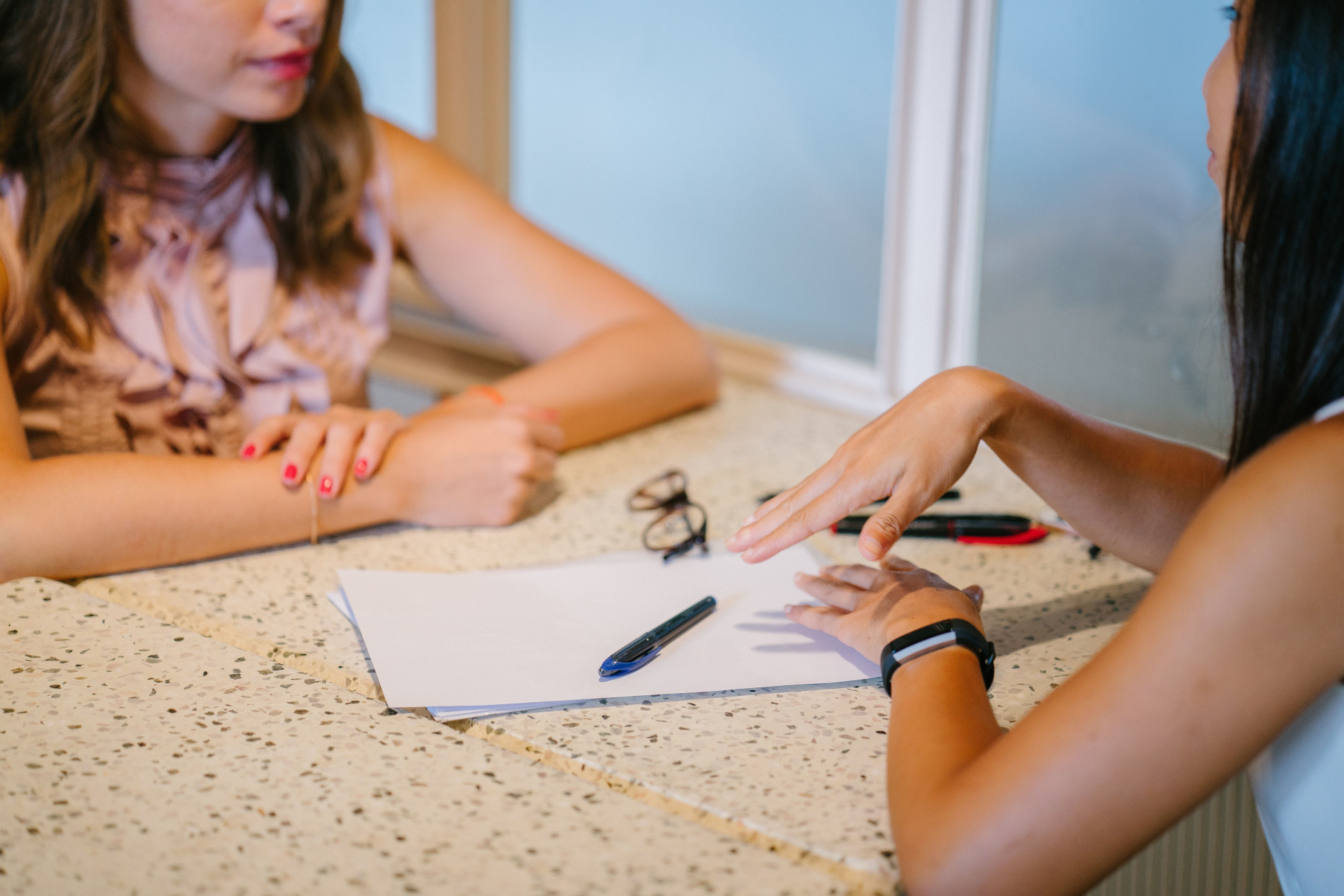 zwei Frauen sitzen sich im Gespräch an einem Tisch gegenüber