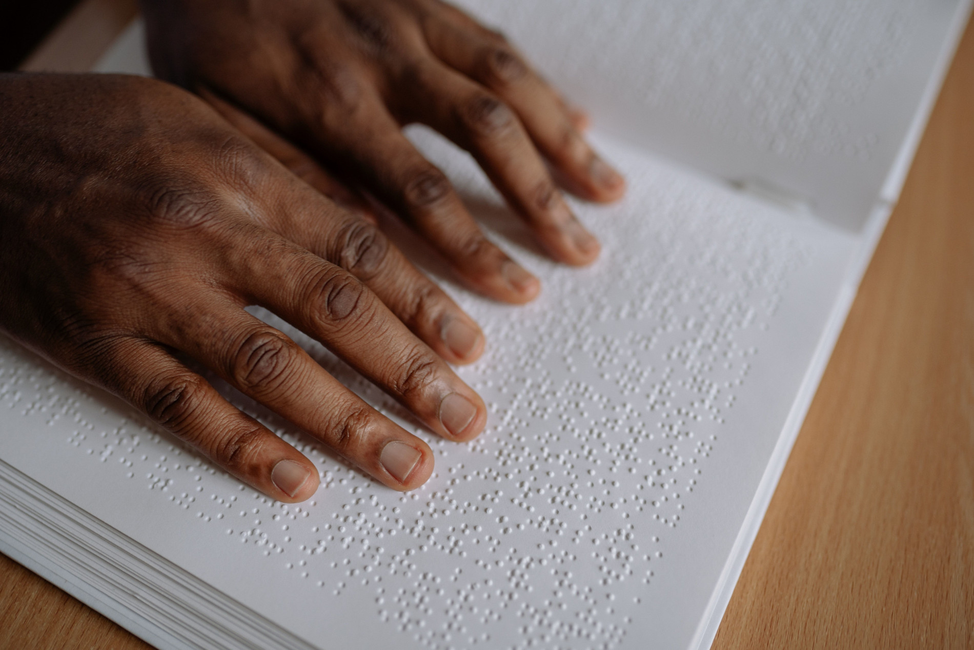 Zwei Hände liegen auf einem Buch mit Bilndenschrift.